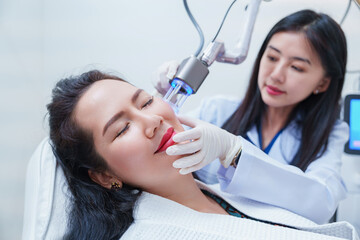 Side view of asian woman getting resurfacing laser fraxel dual and ultrasound face treatment in medical spa center. skin rejuvenation concept	