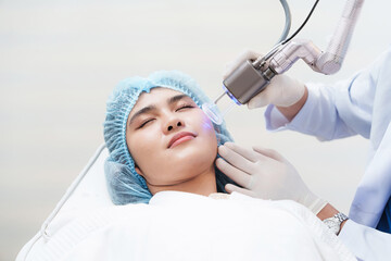 Fototapeta premium Side view of asian woman getting resurfacing laser fraxel dual and ultrasound face treatment in medical spa center. skin rejuvenation concept 