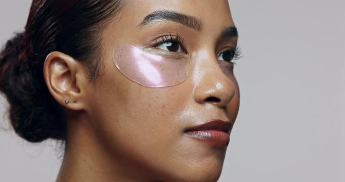 Skincare, woman and face in studio with eye mask, beauty or hyaluronic acid treatment. Girl, thinking and patch on skin for hydration, anti aging and dermatology care on gray background for aesthetic