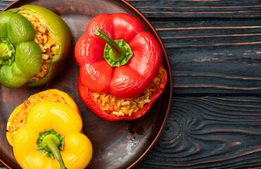 Baked stuffed pepper ( paprika ) with rice , carrot and meat . Top view on rustic background