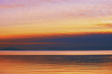 Bright sunset over lake Geneva, Switzerland, golden clouds reflect in the water