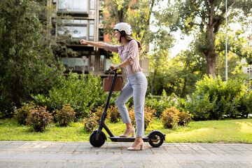 Woman in business suit riding electric scooter commuting to work.