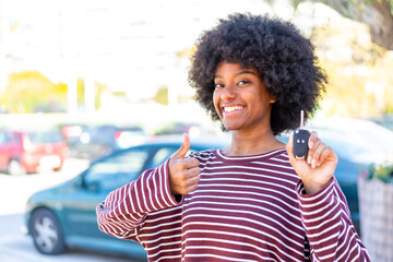 African American girl holding car keys at outdoors with thumbs up because something good has happened