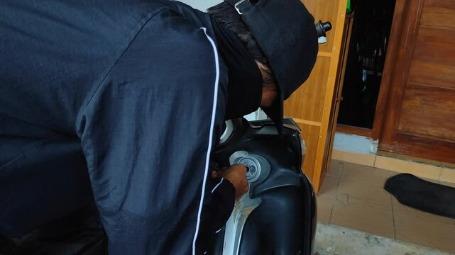 A thief tries to force the motorbike lock open using a screwdriver