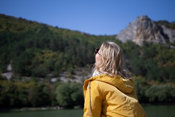 A woman in a yellow jacket is looking out over a mountain range