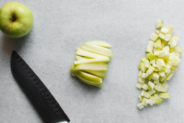 Top view of diced green apples on a marble countertop, overhead view of chopped apples on a white...