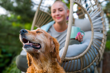 Young female cancer patient relaxing smiling in hanging chair on the patio with her emotional...