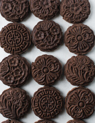 Overhead view of stamped chocolate cookies on a parchment lined baking tray, top view of embossed chocolate sugar cookies on a white background