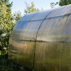 Handmade greenhouse from a metal framework and a polyethylene film on a farmer's land plot....