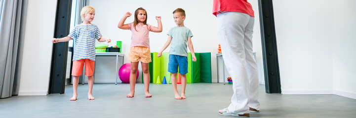 Kids physical therapy. Group of children and female therapist exercising during session. Bilateral...