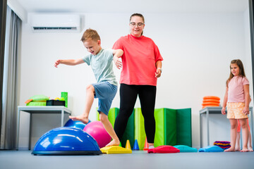 Kids physical therapy. Group of children and female therapist exercising during session. Bilateral...