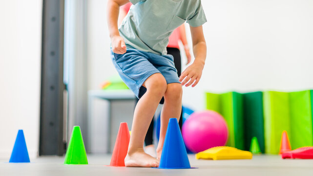Young boy exercising with female physical therapist during therapy session. Child occupational physical therapy. Bilateral coordination.