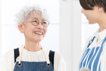 キッチンに立つ若い女性とシニア女性　料理イメージ