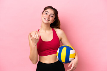 Young caucasian woman playing volleyball isolated on pink background inviting to come with hand. Happy that you came