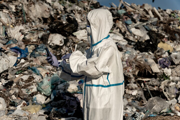 Man in bacteriological protective in a landfill. Open-air landfill. Ecological damage, contaminated land.