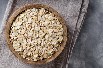 Wooden Bowl with Raw Oat Flakes on Linen Napkin, Vegan Food Concept, Top View, Copy Space