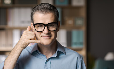 Smiling businessman doing the phone gesture