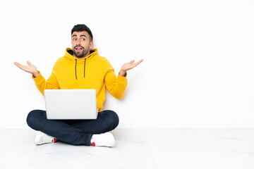 Caucasian man sitting on the floor with his laptop with shocked facial expression