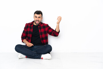 Young handsome man sitting on the floor making guitar gesture