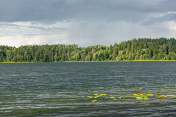 A serene lakeside scene with a lush, forested shoreline and a vibrant rainbow arching across the...