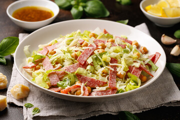 La Scala Salad with romaine lettuce, salami, mozzarella cheese and chickpeas in white plate.