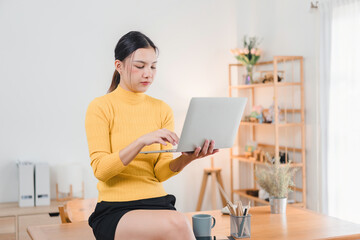 Asian businesswoman working on laptop at home office.