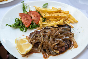 Plate of veal liver with onions, potatoes and salad, in Rhodes Town, Greece.
