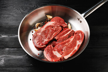 Beef steak in aluminum pan on black wooden table