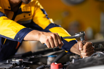 Close up mechanical hand with tools and spanner. Hispanic latin male mechanic repairs car in garage. Car maintenance and auto service garage concept