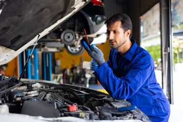 hispanic latin male mechanic repairs car in garage. Closeup hand. Auto car mechanic checking the oil level of the car engine. Car repair and maintenance