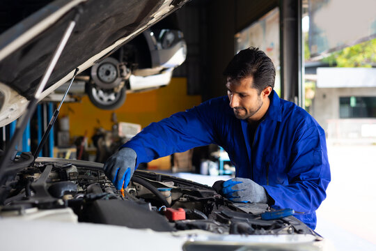 hispanic latin male mechanic repairs car in garage. Closeup hand. Auto car mechanic checking the oil level of the car engine. Car repair and maintenance
