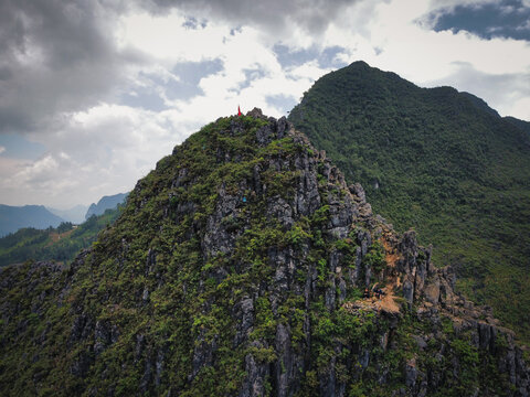 Mountain pass on the Ha Giang Loop with Vietnamese flag waving on top of the rock formations. This pass marks the fronteer between China and Vietnam