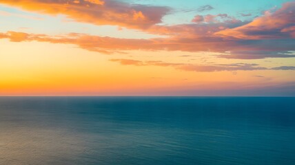 Fototapeta premium A photo of a vibrant sky with teal blue, oranges, and yellows above the ocean horizon. The sky is a gradient of rich colors 
