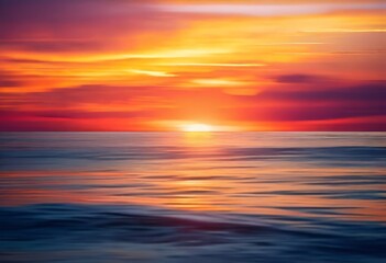 A breathtaking sunset over the ocean, with vibrant hues of orange, yellow, and red reflecting on the calm water surface.
