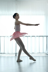 Fototapeta premium Teenage ballerina practices ballet in a pink outfit in a studio