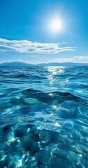 a serene ocean scene with crystal clear water reflecting the bright sun, surrounded by distant mountains under a blue sky with scattered clouds.