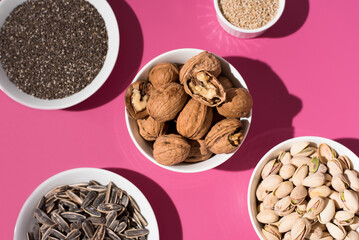 Semillas de chía, sésamo, nueces y pistachos. Frutos secos sobre un fondo rosa. Vista superior