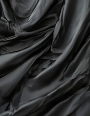 Fototapeta premium a close-up view of a black fabric, possibly silk or satin, with a smooth, flowing texture. The fabric appears to be crumpled, creating a sense of movement and depth.