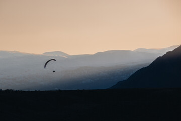paraglider in the mountains at dawn against the backdrop of snowy mountains