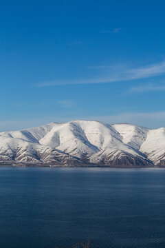 snow capped mountains on lake sevan in clear weather at sunset