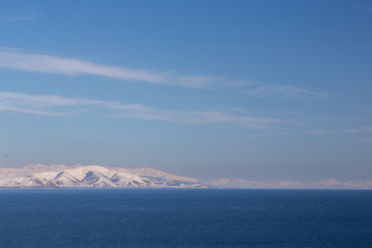 snow capped mountains on lake sevan in clear weather at sunset