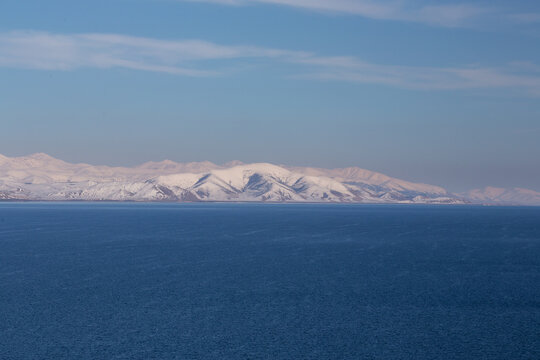 snow capped mountains on lake sevan in clear weather at sunset