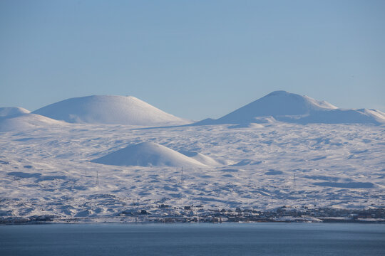 snow capped mountains on lake sevan in clear weather at sunset
