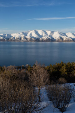 snow capped mountains on lake sevan in clear weather at sunset