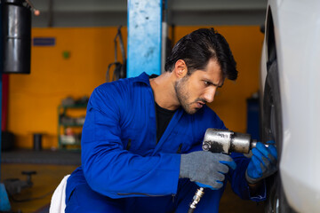 Mechanic car repair and chang tire and wheel by electric drill to loosen the bolts. Car maintenance...