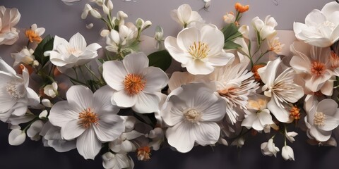 A close-up view of a bouquet of white and orange flowers, including daisies, peonies, and other blooms, arranged against a gray background.