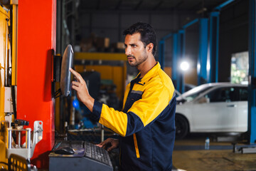 mechanic installing wheel alignment sensor by machine caliper. Hispanic man professional mechanic repairs car in garage. Car maintenance and auto service garage concept