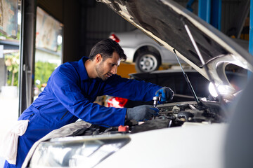 mechanical man working  with tools and spanner. Hispanic latin male mechanic repairs car in garage. Car maintenance and auto service garage concept