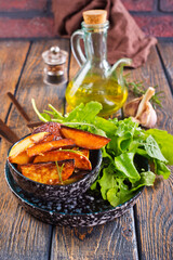 Bowl with baked potatoes on wooden background