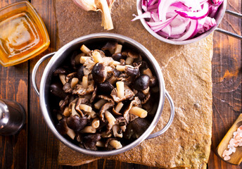 pickled mushrooms in metal bowl on the table, next to spices. pickle mushrooms